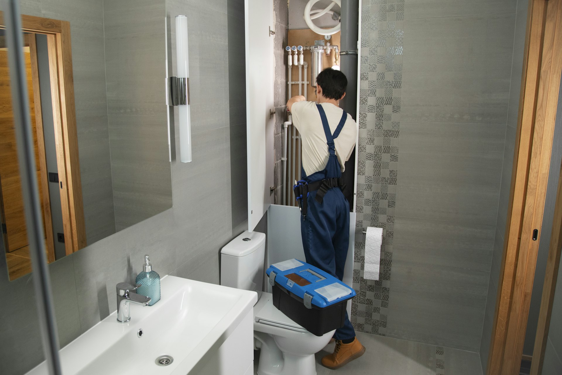 Plumber repairing bathroom plumbing under a sink