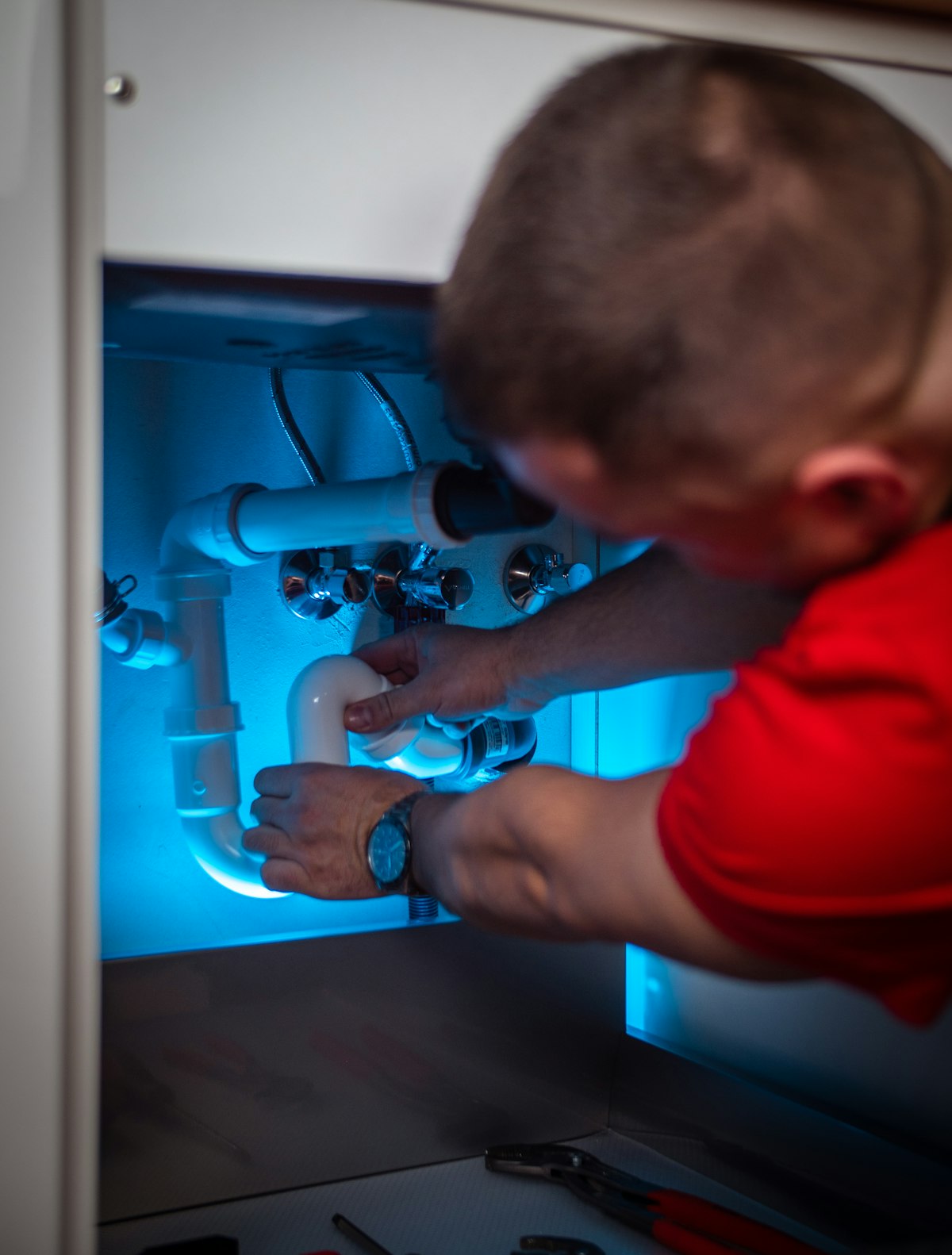Plumber repairing a leak under a kitchen sink